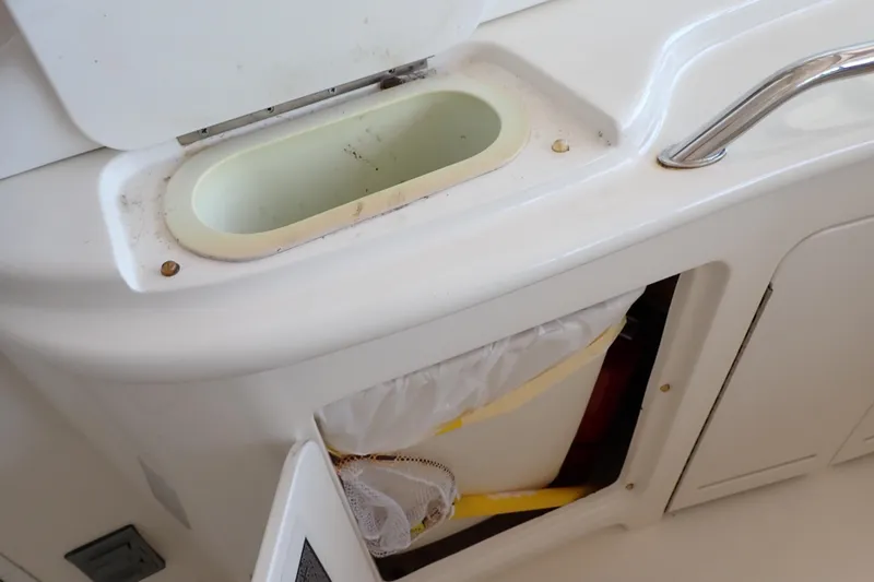Slide: The Image of 2002 Sea Ray 340 Sundancer boat interior with storage compartment and trash bin. - 61