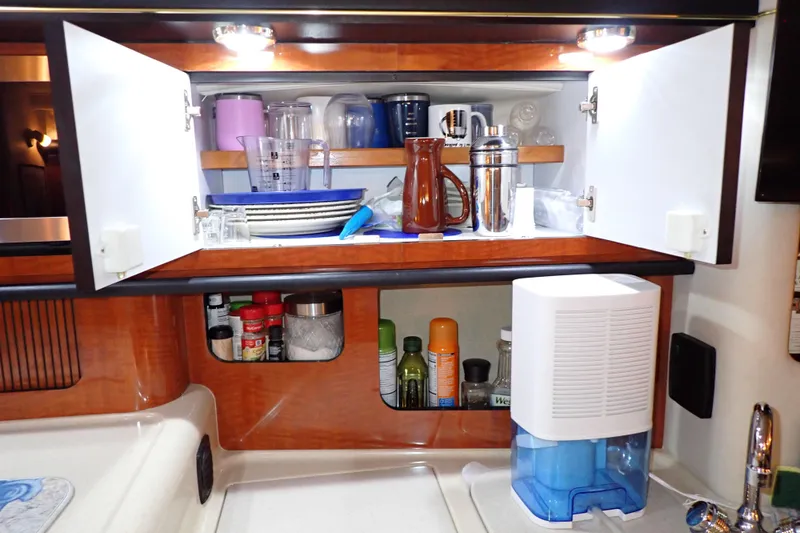 Slide: The Image of Cabin kitchen of 2002 Sea Ray 340 Sundancer with open cabinets and kitchenware. - 76