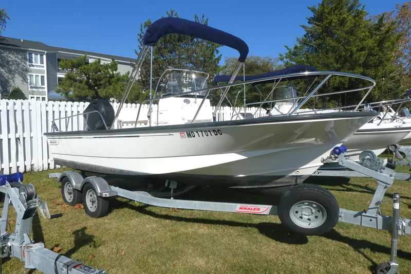 The Image of 2010 Boston Whaler 190 Montauk boat on trailer, parked on grass near white fence. - 0