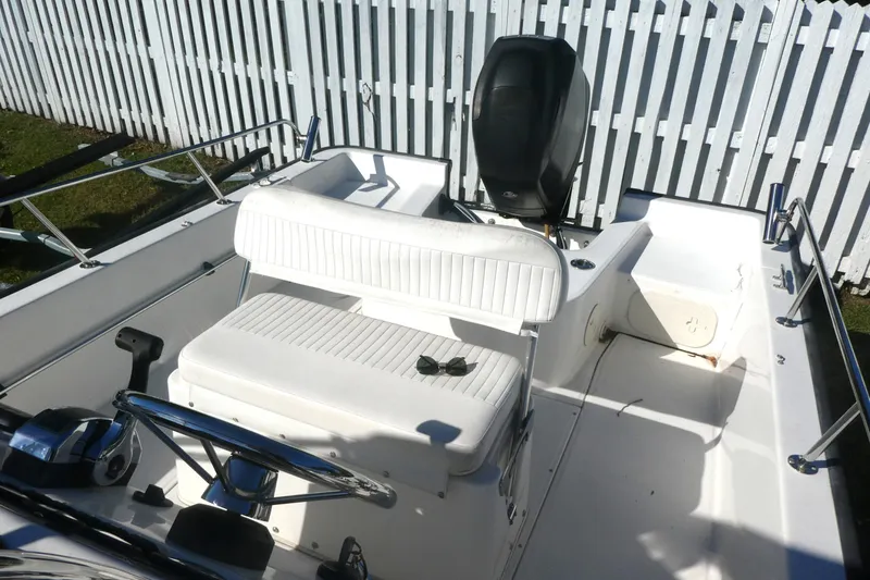Slide: The Image of 2010 Boston Whaler 190 Montauk boat interior with white seating and steering wheel. - 4