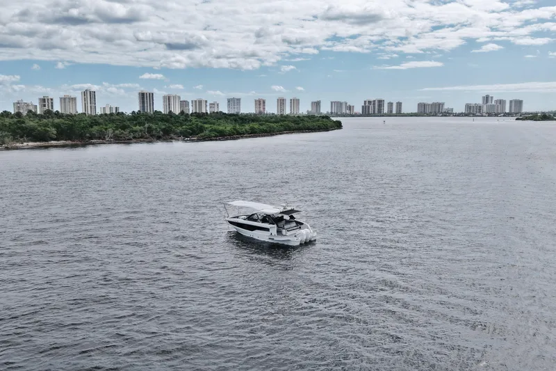 Slide: The Image of 2023 Galeon 400 XL yacht cruising on a wide river with city skyline backdrop. - 44