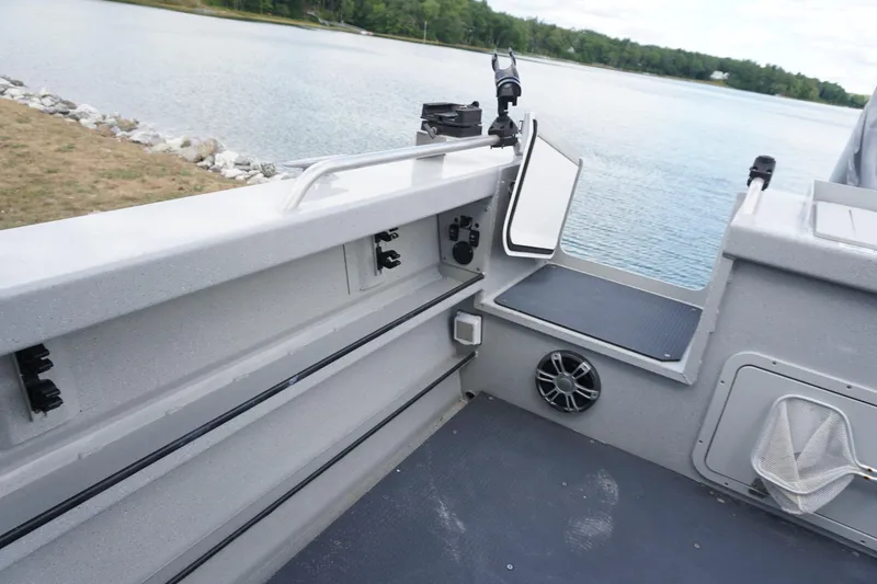Slide: The Image of 2023 Weldcraft 220 Ocean King boat interior with rod holders and speaker, near a serene lake. - 8