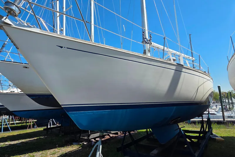 Slide: The Image of 1986 Sabre 34 sailboat on stands, white hull with blue stripe, clear sky background. - 31
