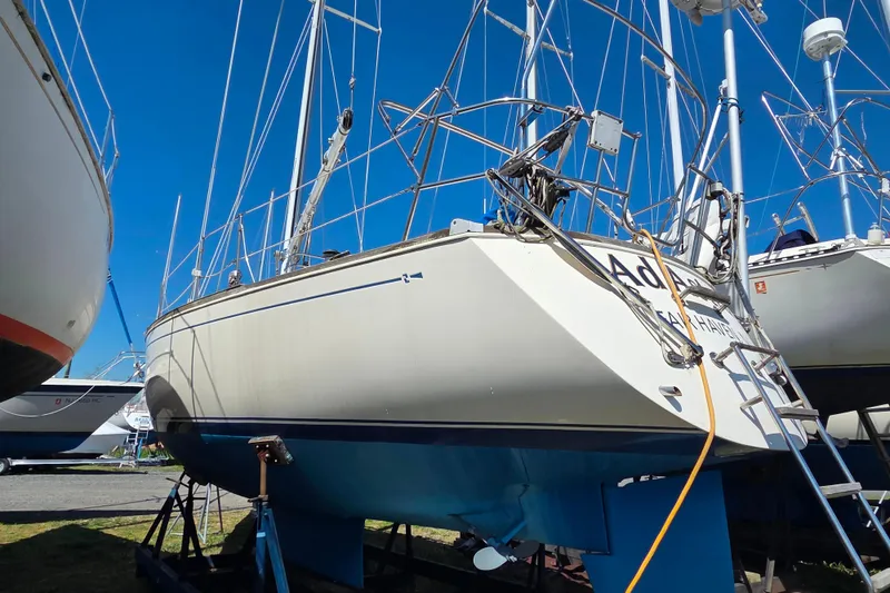 Slide: The Image of 1986 Sabre 34 sailboat on dry dock, surrounded by other boats, under clear blue sky. - 35