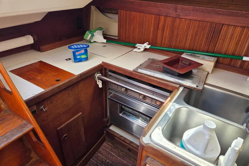 Slide: The Image of 1986 Sabre 34 yacht galley with stove, sink, and cleaning supplies. - 41