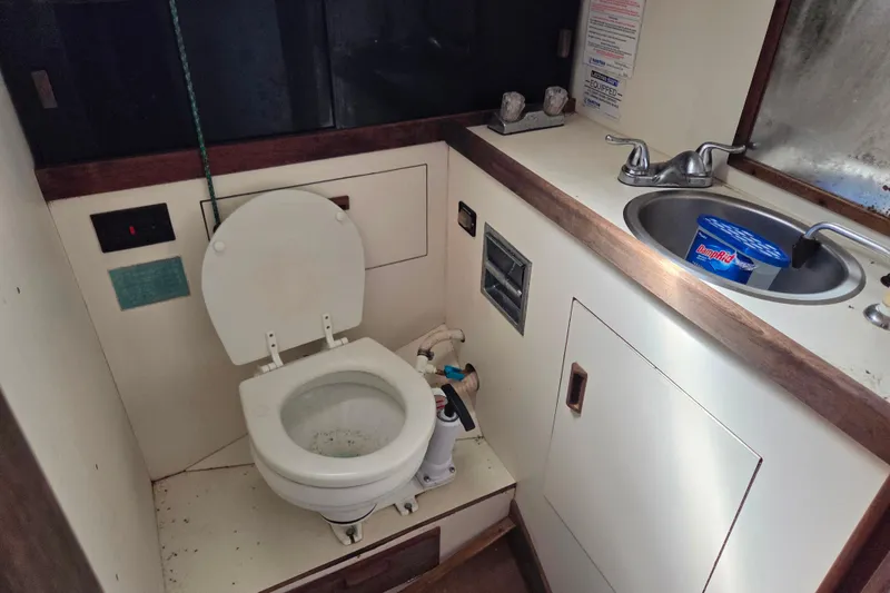 Slide: The Image of 1986 Sabre 34 yacht bathroom with toilet, sink, and storage cabinet. - 45