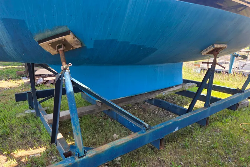 Slide: The Image of 1986 Sabre 34 sailboat hull on a metal cradle, resting on grass. - 51
