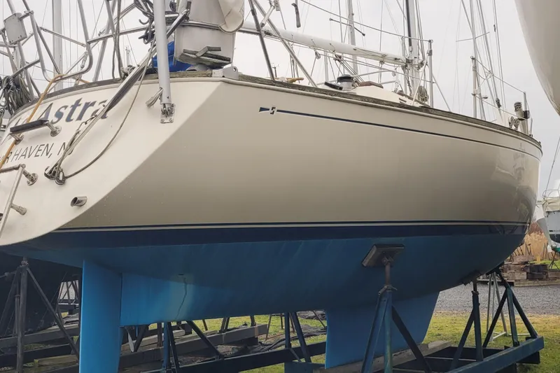 Slide: The Image of 1986 Sabre 34 sailboat on stands, white hull with blue bottom, docked outdoors. - 9