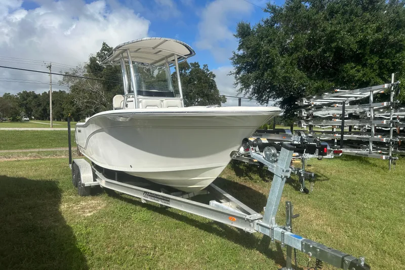 The Image of 2023 Sea Fox 228 Commander boat on trailer, parked on grass under a blue sky. - 1