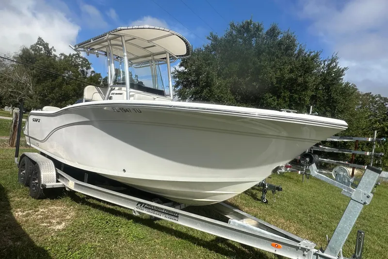 Slide: The Image of 2023 Sea Fox 228 Commander boat on trailer, parked on grass under blue sky. - 2