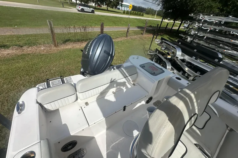 Slide: The Image of 2023 Sea Fox 228 Commander boat interior with seating and motor, parked on grass. - 20