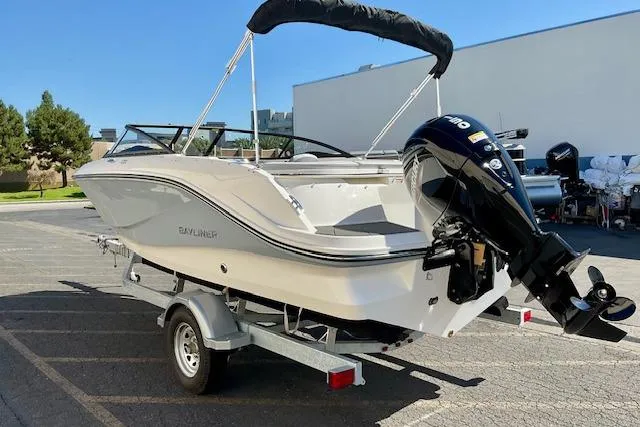 Slide: The Image of 2025 Bayliner V20 boat on trailer with outboard motor, parked outdoors. - 16