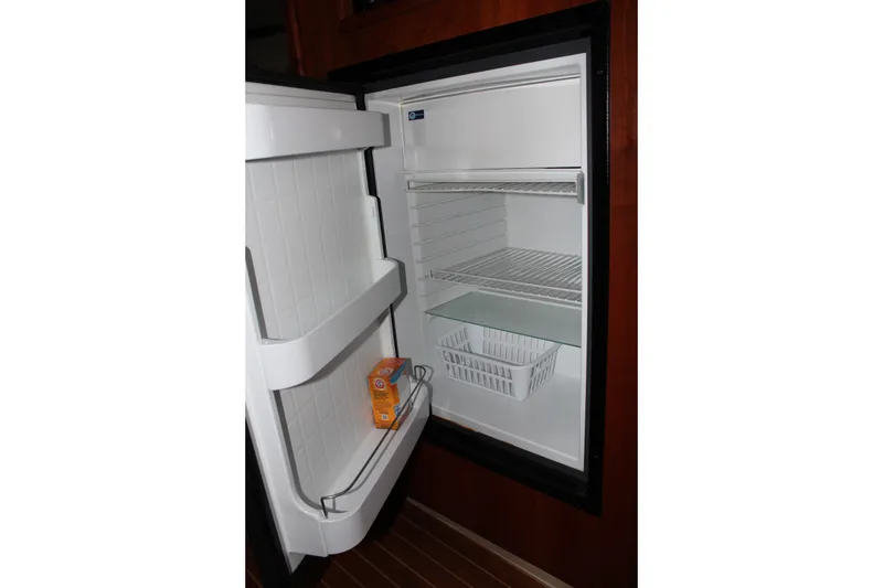 Slide: The Image of Open refrigerator inside 2005 Rampage 38 Express boat, featuring shelves and a door compartment. - 25