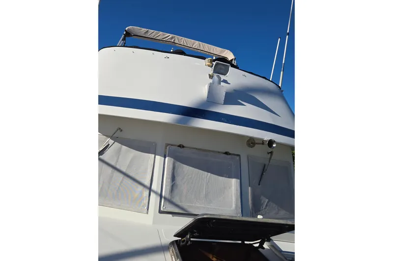 Slide: The Image of 1983 Custom Present 38 Double Cabin Trawler, white exterior, blue stripe, clear sky background. - 17