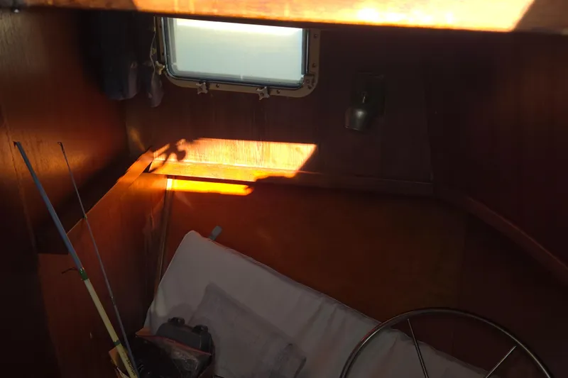 Slide: The Image of 1983 Custom Present 38 Double Cabin Trawler interior with fishing rods and sunlight through window. - 19
