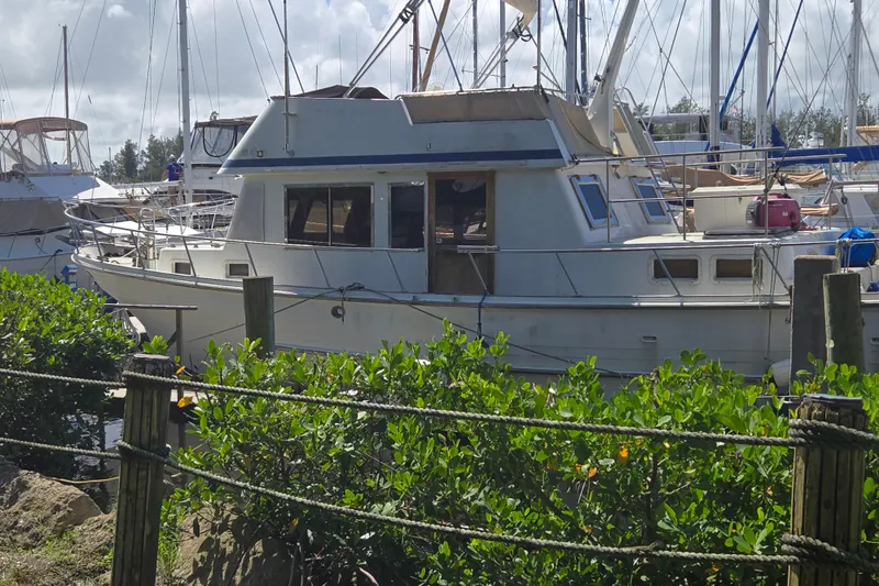 Slide: The Image of 1983 Custom Present 38 Double Cabin Trawler docked at marina, surrounded by greenery. - 3