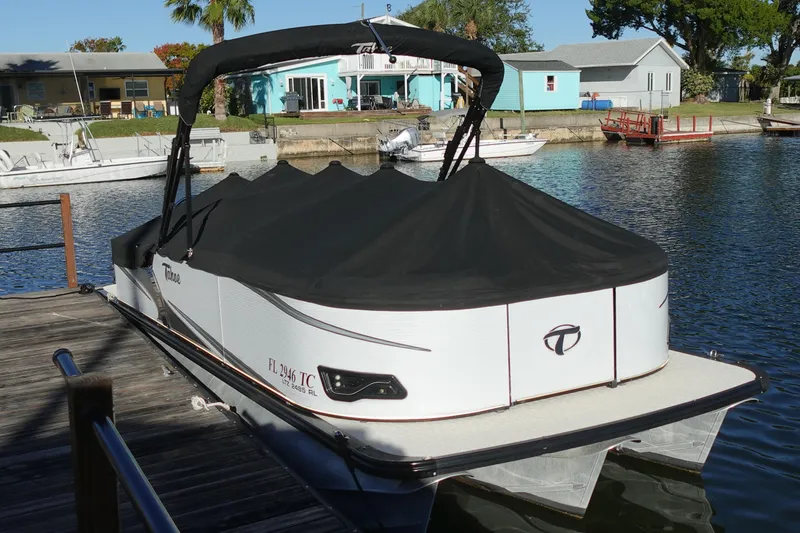 The Image of 2020 Tahoe Pontoon 2485 LTZ Rear Lounger docked with cover on a sunny day. - 0
