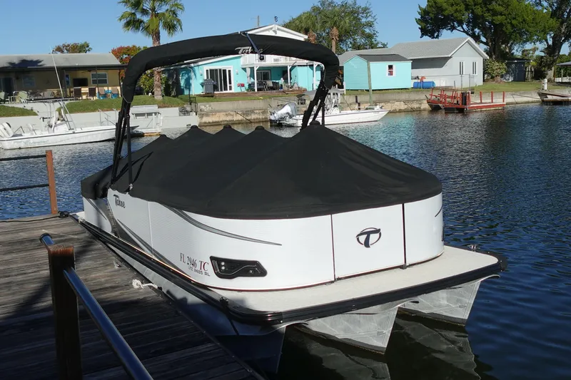 Slide: The Image of 2020 Tahoe Pontoon 2485 LTZ Rear Lounger docked, covered, with scenic waterfront background. - 50