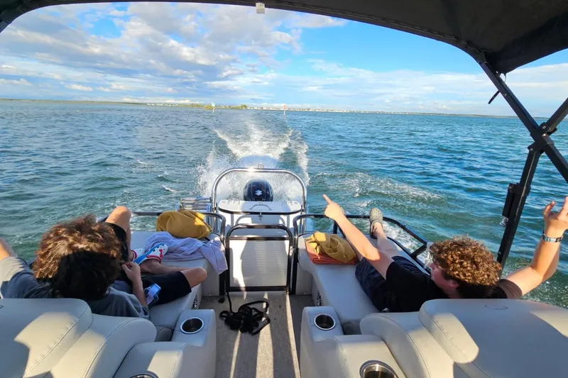 Slide: The Image of 2020 Tahoe Pontoon 2485 LTZ Rear Lounger cruising on open water with passengers relaxing. - 9