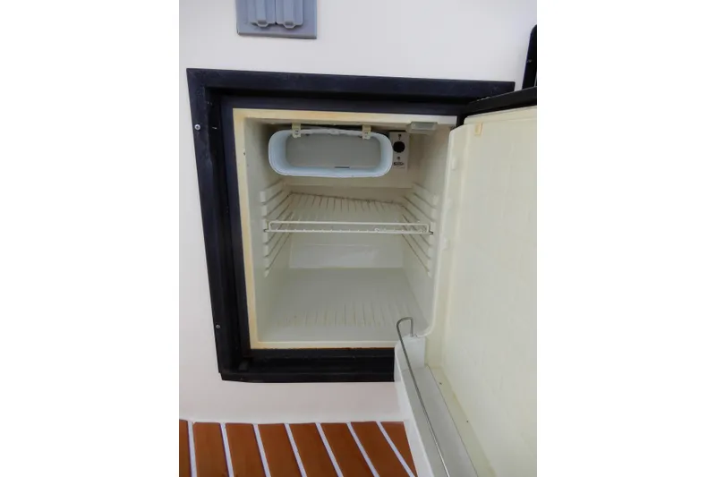 Slide: The Image of Open mini fridge on 2005 Rinker 360 Express Cruiser boat, showing empty interior. - 12