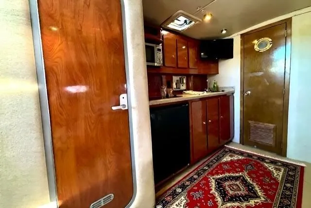 Slide: The Image of Interior of 2005 Rinker 360 Express Cruiser with wood cabinetry and red patterned rug. - 20