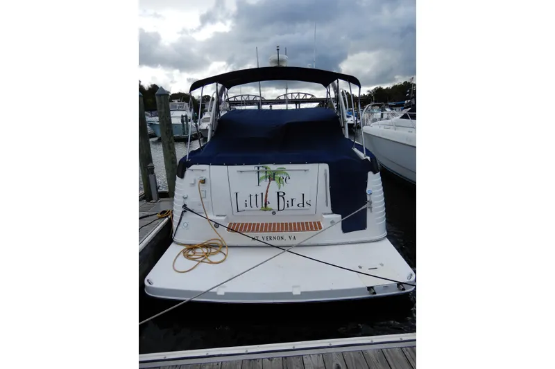 Slide: The Image of 2005 Rinker 360 Express Cruiser docked, rear view with cover, named "Three Little Birds". - 3