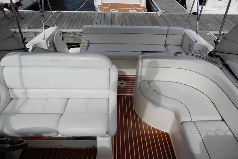 Slide: The Image of 2005 Rinker 360 Express Cruiser interior with white seating and wooden deck. - 7