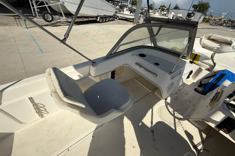 Slide: The Image of 2002 Boston Whaler Ventura 160 interior with seating and dashboard, docked at a marina. - 9