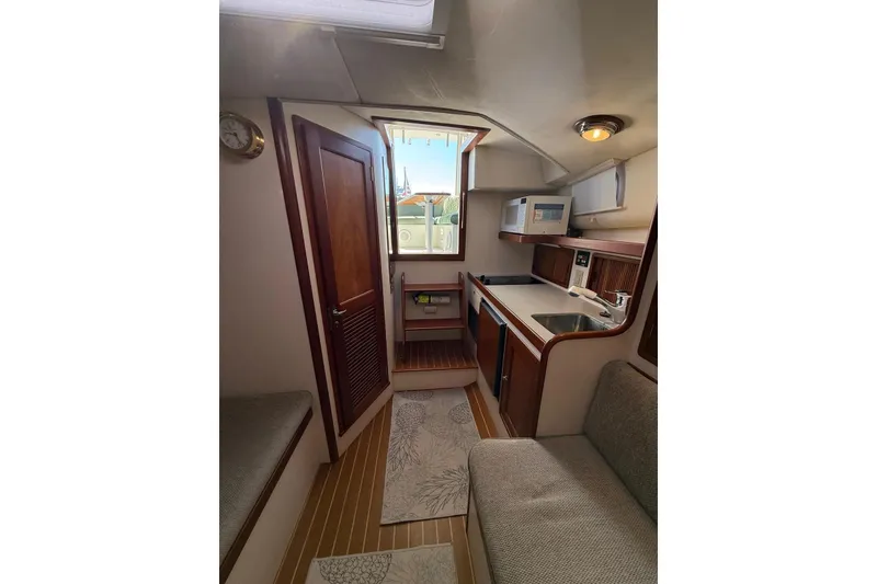 Slide: The Image of Interior of 2000 Little Harbor Whisper Jet 34, featuring compact kitchen and seating area. - 11