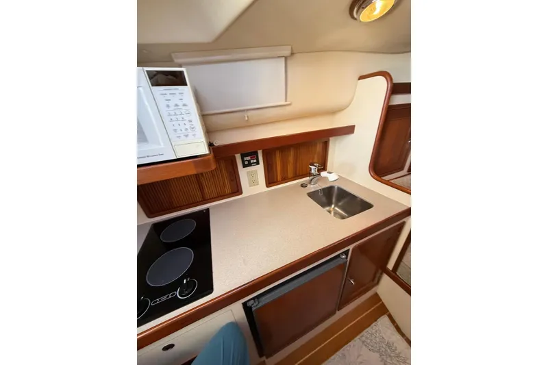 Slide: The Image of Interior of 2000 Little Harbor Whisper Jet 34, featuring a compact kitchen with sink and stove. - 13