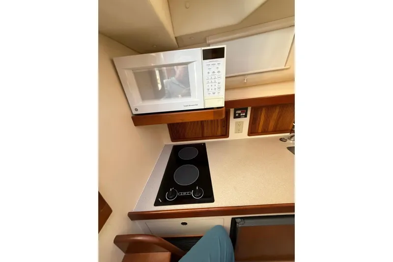 Slide: The Image of Compact kitchen area in a 2000 Little Harbor Whisper Jet 34 boat, featuring a microwave and stovetop. - 14