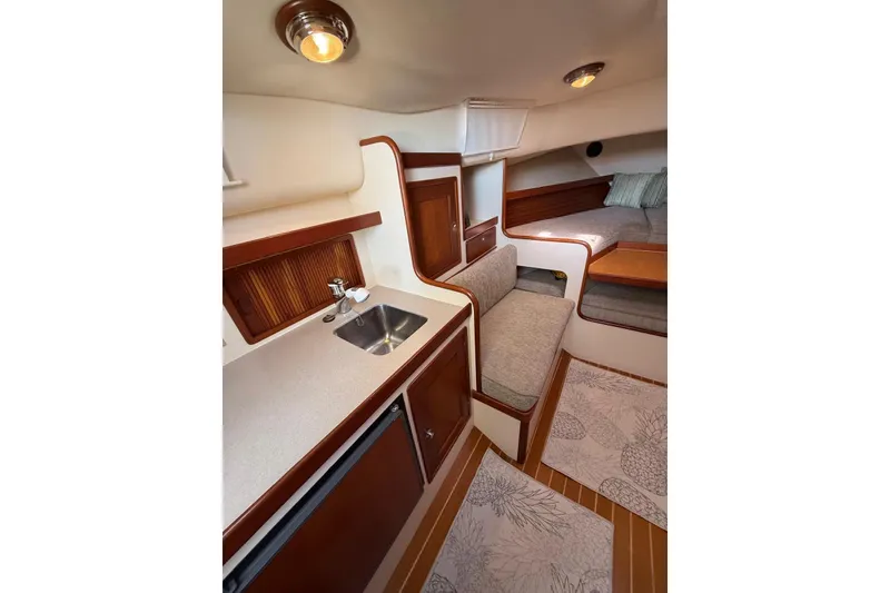 Slide: The Image of Interior of 2000 Little Harbor Whisper Jet 34, featuring cozy seating and compact kitchenette. - 15