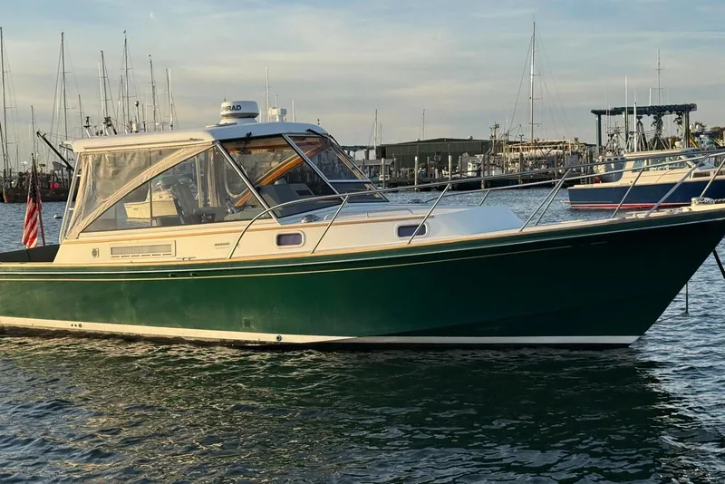 Slide: The Image of 2000 Little Harbor Whisper Jet 34 boat docked in marina, green hull, clear sky. - 24