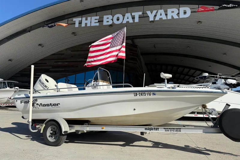 Slide: The Image of 2002 Fishmaster 196 Travis Edition boat on trailer, American flag, outside The Boat Yard. - 2