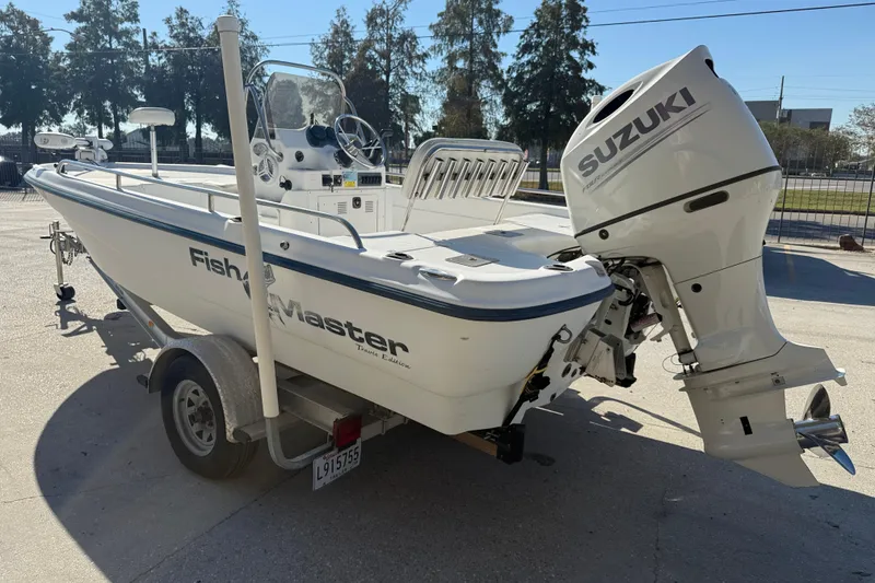 Slide: The Image of 2002 Fishmaster 196 Travis Edition boat with Suzuki outboard motor, parked on a trailer. - 6