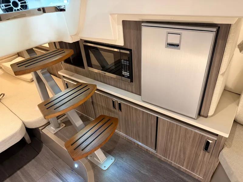 Slide: The Image of 2023 Sea Ray Sundancer 320 Outboard interior with steps, microwave, and compact fridge. - 27