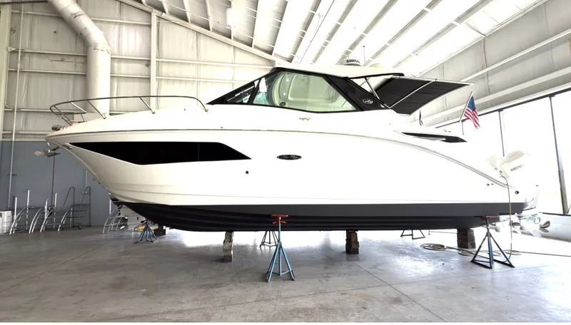 Slide: The Image of A 2023 Sea Ray Sundancer 320 Outboard is on stands in a warehouse. - 0