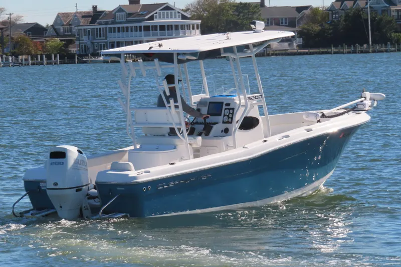 The Image of 2023 Clearwater 2200 CC boat cruising on a sunny day near waterfront homes. - 0