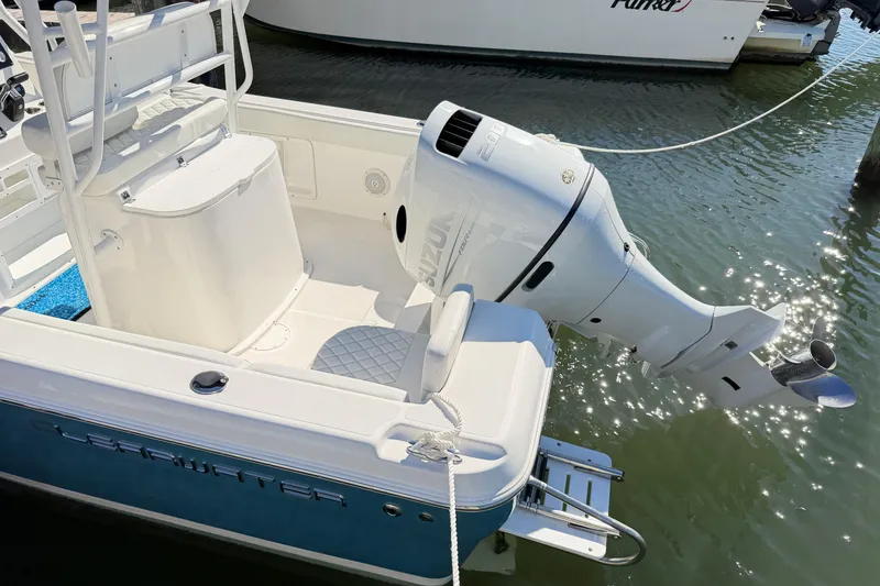 Slide: The Image of 2023 Clearwater 2200 CC boat with Suzuki outboard motor docked in sunlight. - 2