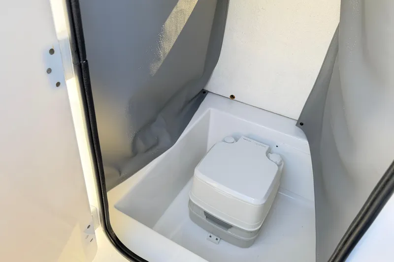 Slide: The Image of 2023 Clearwater 2200 CC boat interior with portable toilet in enclosed space. - 17
