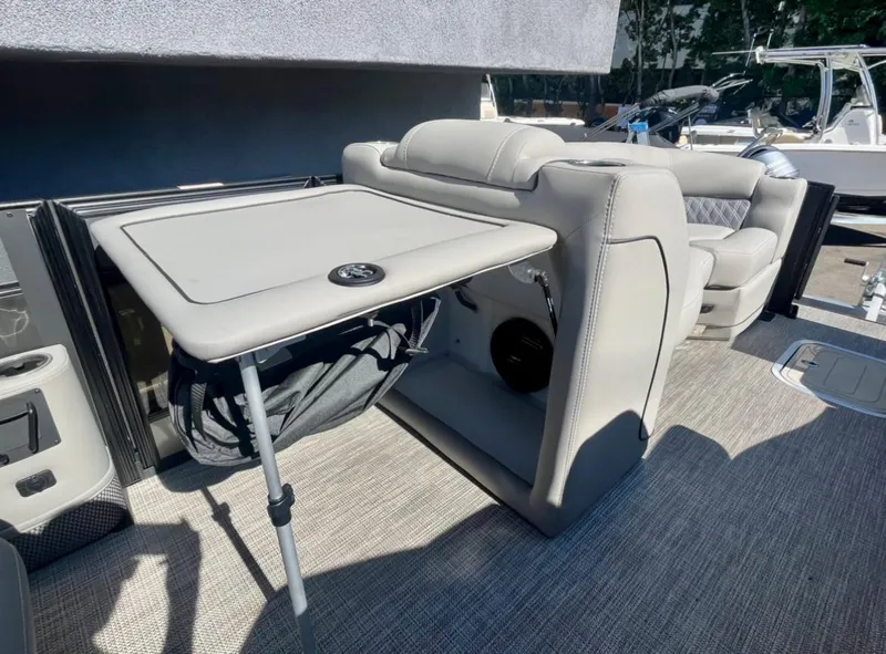 Slide: The Image of 2025 Barletta Lusso 23UC boat interior with a foldable table and cushioned seating. - 10