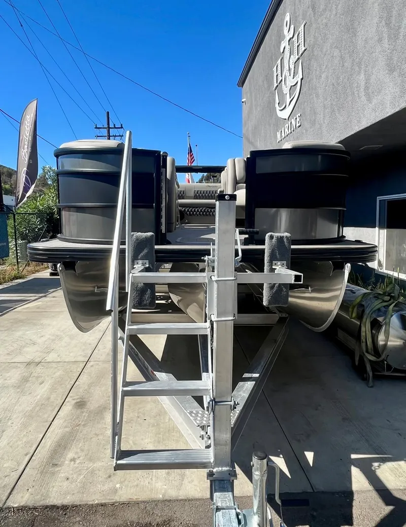 Slide: The Image of 2025 Barletta Lusso 23UC pontoon boat on trailer outside marine dealership. - 22