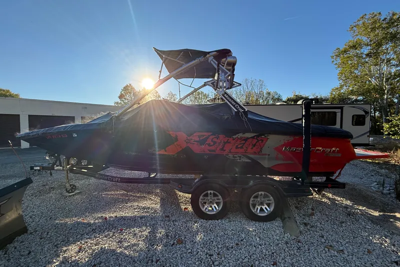 Slide: The Image of 2008 MasterCraft XStar 23 boat on trailer, covered, with sun setting in the background. - 3