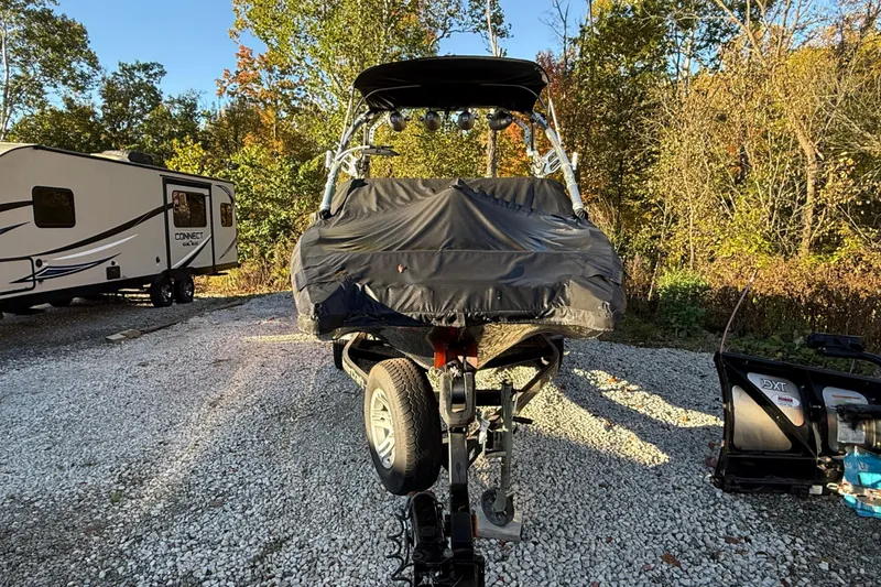 Slide: The Image of 2008 MasterCraft XStar 23 boat covered, parked on gravel near RV and trees. - 6