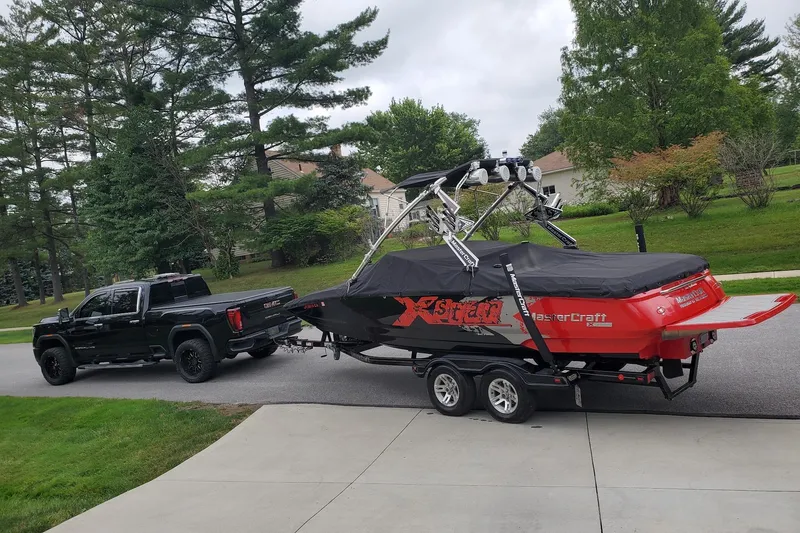 Slide: The Image of Black truck towing a 2008 MasterCraft XStar 23 boat on a suburban street. - 9