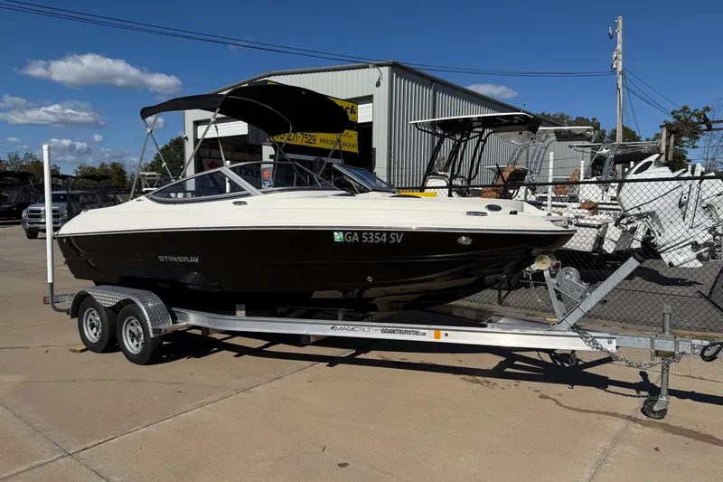 The Image of 2019 Stingray 198 LX boat on trailer, parked outdoors under clear blue sky. - 0
