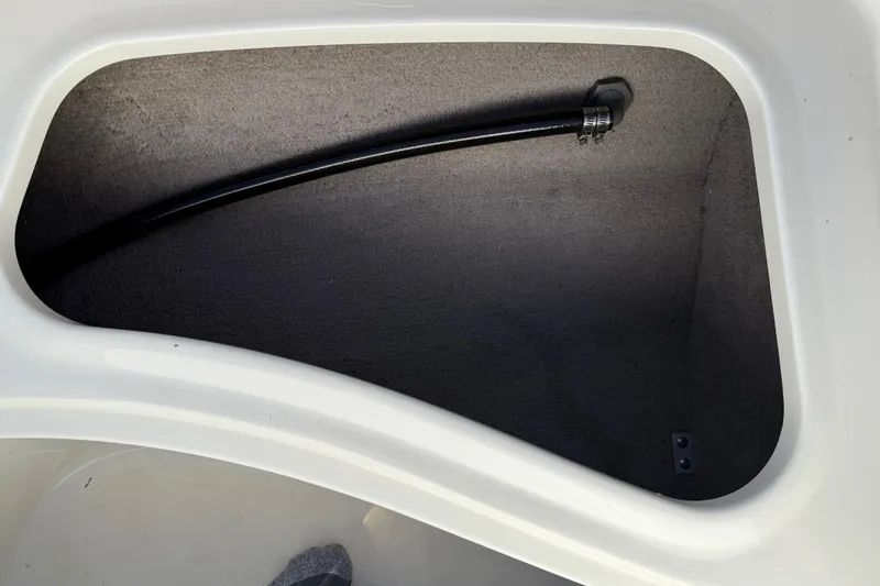 Slide: The Image of Storage compartment in 2019 Stingray 198 LX boat, featuring a black hose. - 15