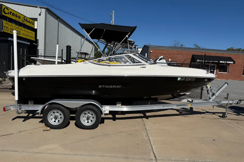 Slide: The Image of 2019 Stingray 198 LX boat on trailer, parked outside dealership under clear blue sky. - 2