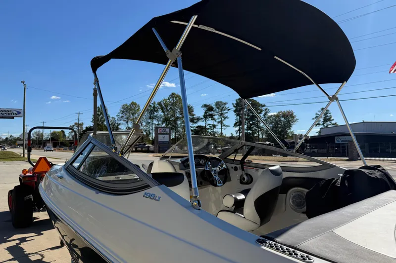 Slide: The Image of 2019 Stingray 198 LX boat with canopy, parked outdoors on a sunny day. - 49