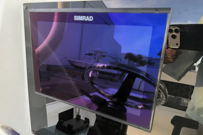 Slide: The Image of Simrad display on 2023 Tidewater 2410 Bay Max boat, reflecting steering wheel and surroundings. - 39